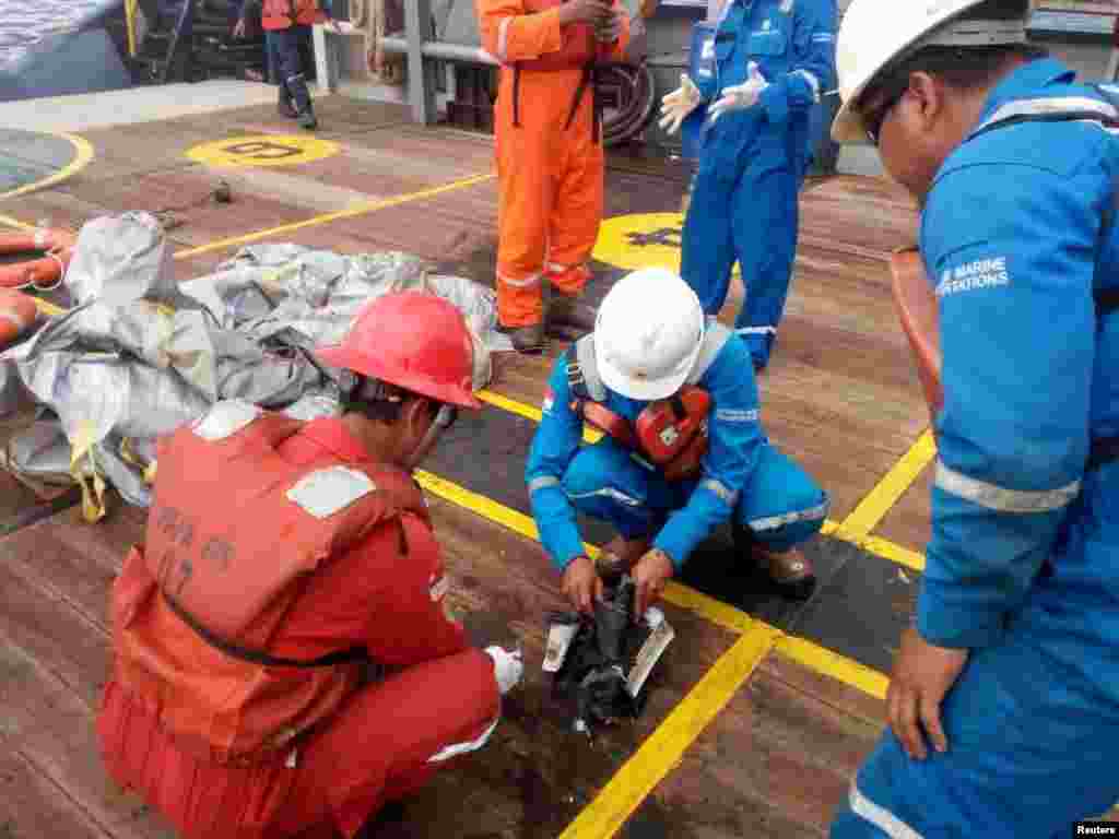 Sejumlah karyawan PT. Pertamina memeriksa beberapa serpihan yang berhasil diangkat yang dipercaya berasal dari pesawat Lion Air nomor penerbangan JT610 yang jatuh, di atas kapal Prabu milik PT. Pertamina, di lepas pantai Karawang, Jawa Barat, 29 Oktober 2018.