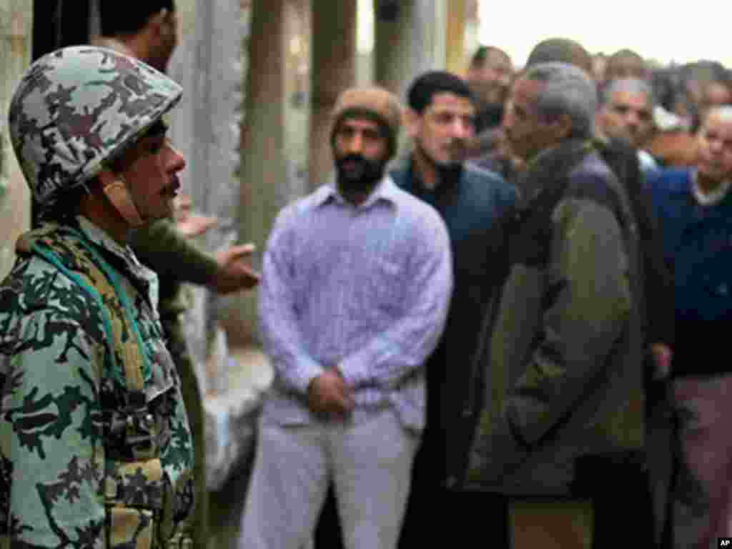An Egyptian soldier stands guard as voters wait outside a polling center south of Cairo on November 28, 2011. (AP)