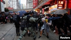 A riot police officer clashes with a protester during an anti-government rally in central Hong Kong, China October 6, 2019.