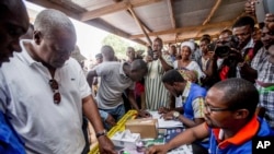 Ghana Incumbent President, John Dramani Mahama candidate of the National Democratic Congress, second left, validates his name before casting his vote during the Presidential and parliamentary election, in Bole Ghana, Wednesday, Dec. 7, 2016.