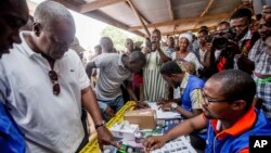 Presiden Ghana John Dramani Mahama (kiri) memberikan suara di TPS di Bole, Ghana, Rabu (7/12).