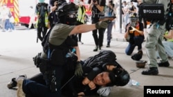 A police officer raises his pepper spray handgun as he detains a man during a march against the national security law at the anniversary of Hong Kong's handover to China from Britain in Hong Kong, July 1, 2020.
