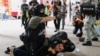 A police officer raises his pepper spray handgun as he detains a man during a march against the national security law at the anniversary of Hong Kong&#39;s handover to China from Britain.