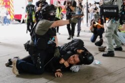 A police officer raises his pepper spray handgun as he detains a man during a march against the national security law at the anniversary of Hong Kong's handover to China from Britain in Hong Kong, July 1, 2020.