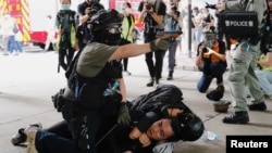 A police officer raises his pepper spray handgun as he detains a man during a march against the national security law at the anniversary of Hong Kong's handover to China from Britain in Hong Kong, July 1, 2020.