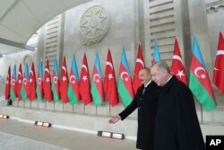 Turkey's President Recep Tayyip Erdogan, right, is welcomed by Azerbaijan's President Ilham Aliyev, center, in Baku, Azerbaijan, Thursday, Dec. 10, 2020. The parade was held in celebration of the peace deal with Armenia over Nagorno-Karabakh, with…