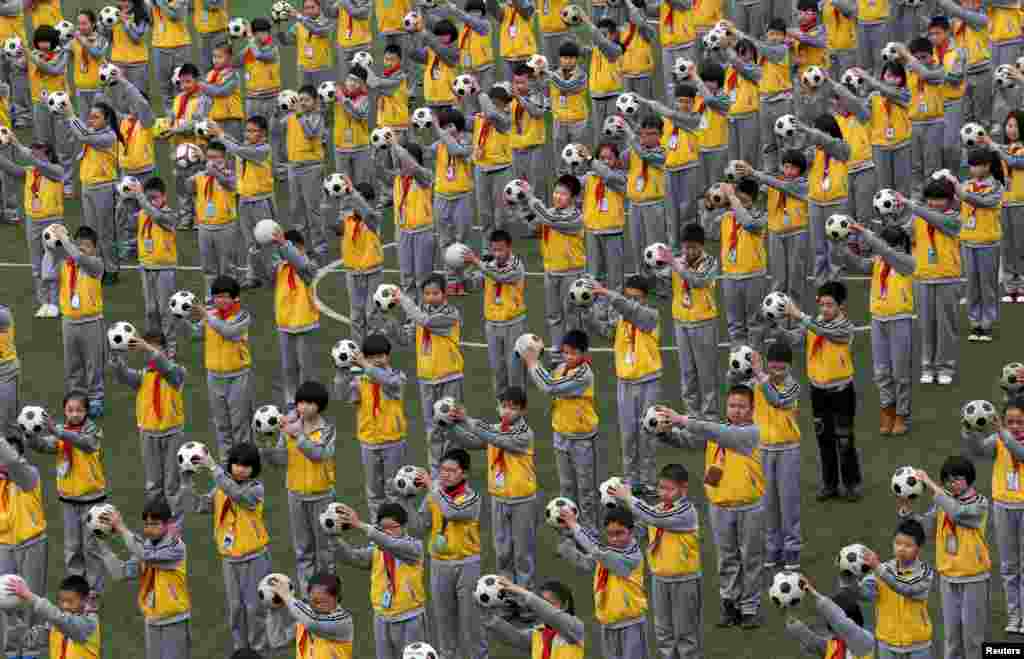 Students do morning exercises with soccer balls on a playground at a primary school in Linhai, Zhejiang province, China.