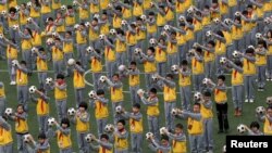 FILE - Students do morning exercises with soccer balls on a playground at a primary school in Linhai, Zhejiang province, March 26, 2015.