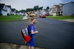 FILE - Paul Adamus, 7, waits at the bus stop for the first day of school in Dallas, Ga., Aug. 3, 2020.