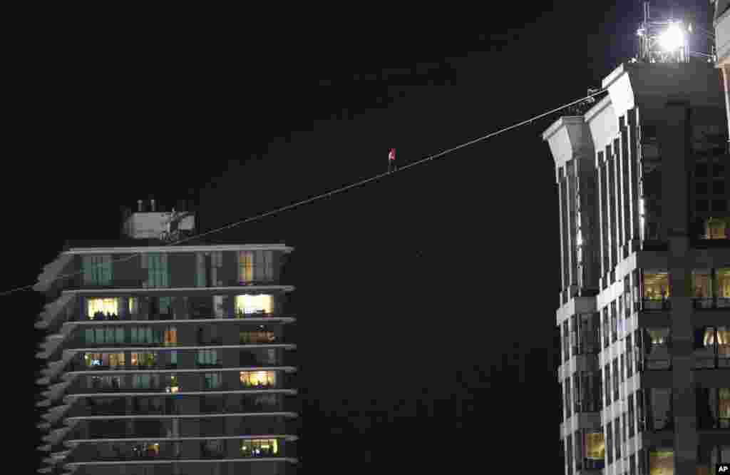 Daredevil Nik Wallenda makes his tightrope walk uphill at a 19-degree angle, from the Marina City west tower across the Chicago River to the top of the Leo Burnett Building, past the Aqua Building (background), in Chicago, Nov. 2, 2014.