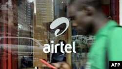 A man with his phone in hand walks past a window branded in an 'Airtel' logo on May 20, 2011 in the Kenyan capital, Nairobi. 