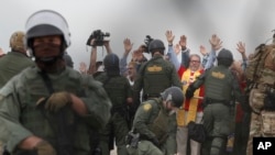 US Border Patrol agents make arrests during a pro-migration protest by members of various faith groups showing support for Central American asylum-seekers who arrived in recent caravans and calling for an end to migrant detentions and deportations, in San Diego as seen through th