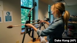 In this June 1, 2017, photo, Michelle Bebber, a PhD archeology student at Kent State University, loads a bow with a recreated ancient arrow in Kent, Ohio.