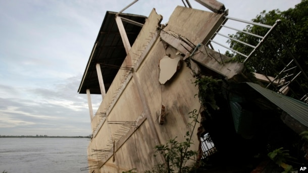 A local house damaged by floods leans toward the Mekong River in Koh Norea village in Phnom Penh, Cambodia, Thursday, Dec. 8, 2011.