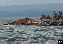 Rescuers help passengers from a capsized ferry boat, center, in Ormoc city on Leyte Island, Philippines, July 2, 2015.