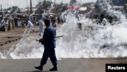 FILE - A policeman walks away after throwing a teargas canister at protesters rallying against Burundi President Pierre Nkurunziza and his bid for a third term, in Bujumbura, Burundi, June 2, 2015.