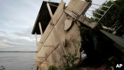 FILE - A local house damaged by floods leans toward the Mekong River in Koh Norea village in Phnom Penh, Cambodia, Thursday, Dec. 8, 2011.