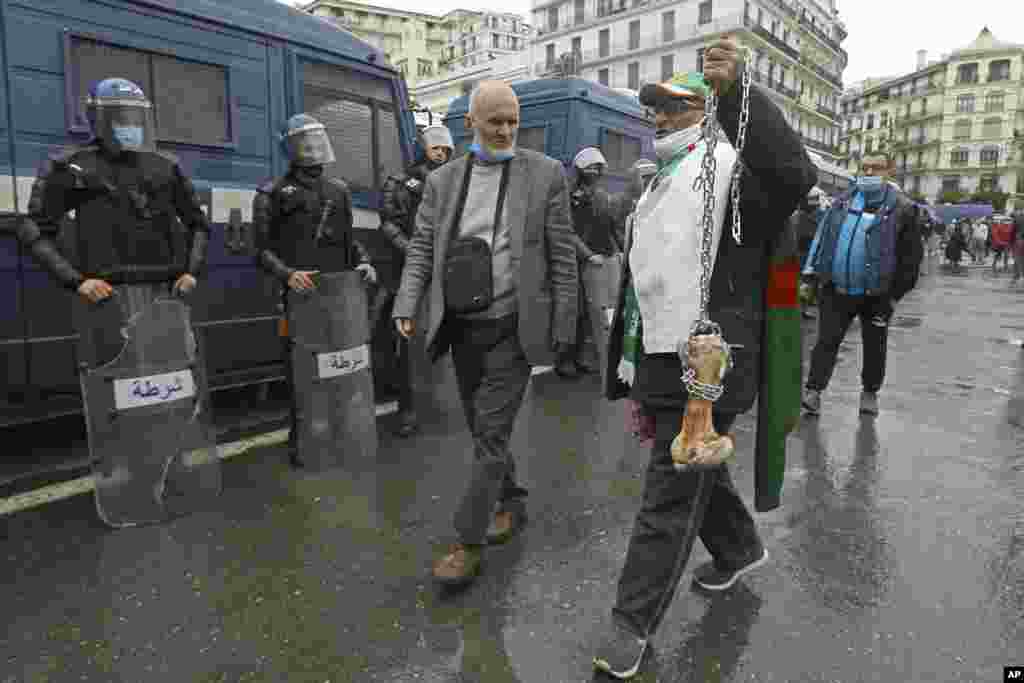 A man holds a bone while shouting &quot;That&#39;s what&#39;s left for those who vote for the President&quot; as Algerians demonstrate in Algiers to mark the second anniversary of the Hirak movement.