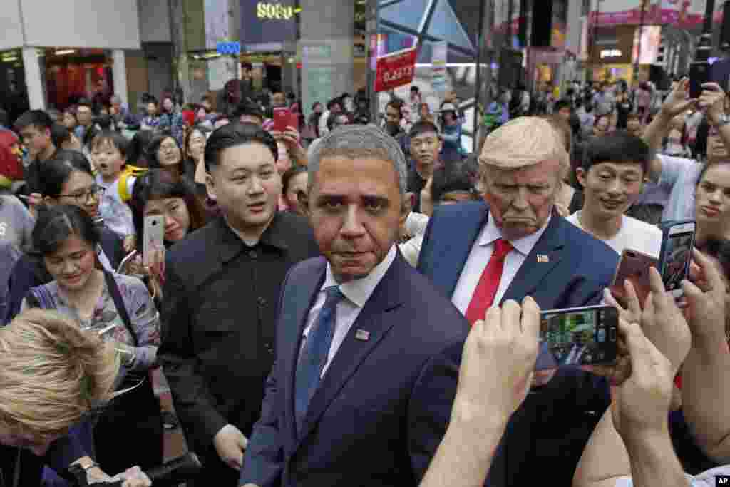 Tiga orang pria dengan wajah mirip Kim Jong Un, mantan Presiden AS Barack Obama dan Presiden AS Donald Trump berpose dengan warga Hong Kong yang menghadiri promosi olahraga rugby.