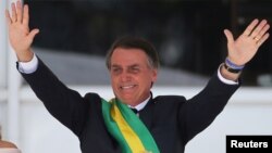 FILE - Brazil's new President Jair Bolsonaro gestures after receiving the presidential sash from outgoing President Michel Temer at the Planalto Palace, in Brasilia, Brazil, Jan. 1, 2019. 