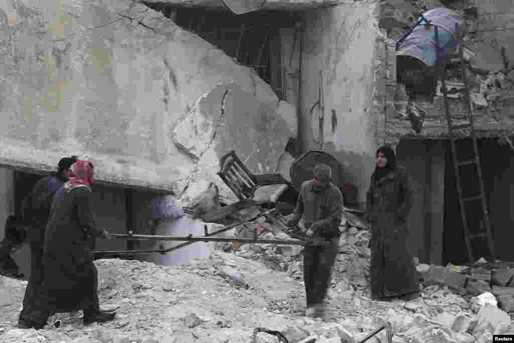 Civilians carry belongings from rubble after what activists said was shelling by forces loyal to Syrian President Bashar al-Assad, Jazmati, Aleppo, Jan. 23, 2014. 