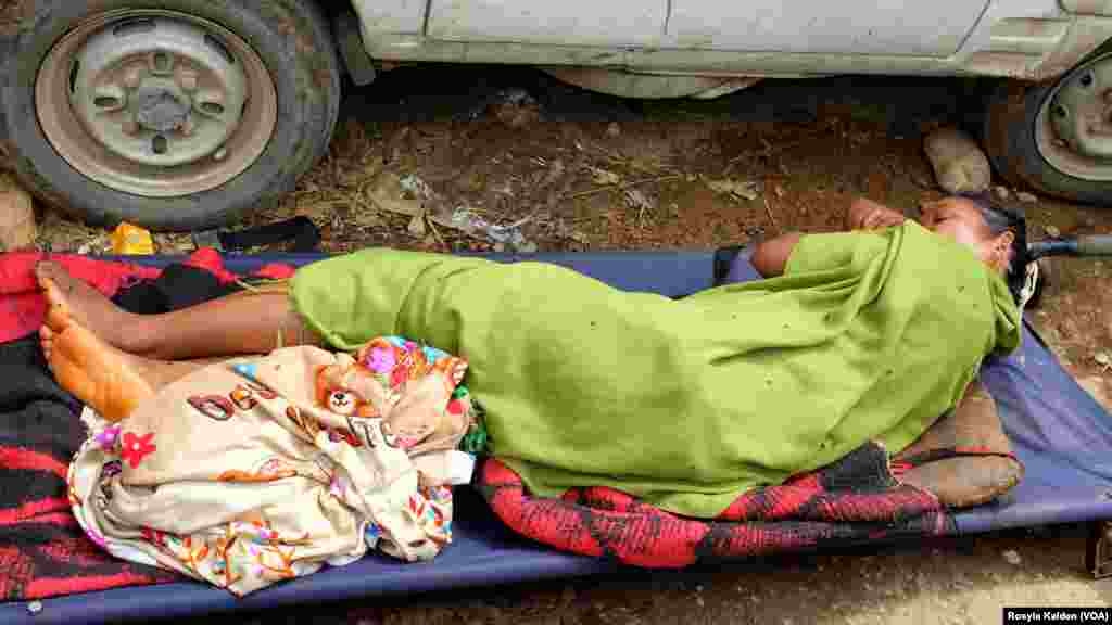 A woman, extricated from the rubble of her home after being trapped for five days, was carried to the roadside to await transportation to a medical center. She was thought to have a broken back.