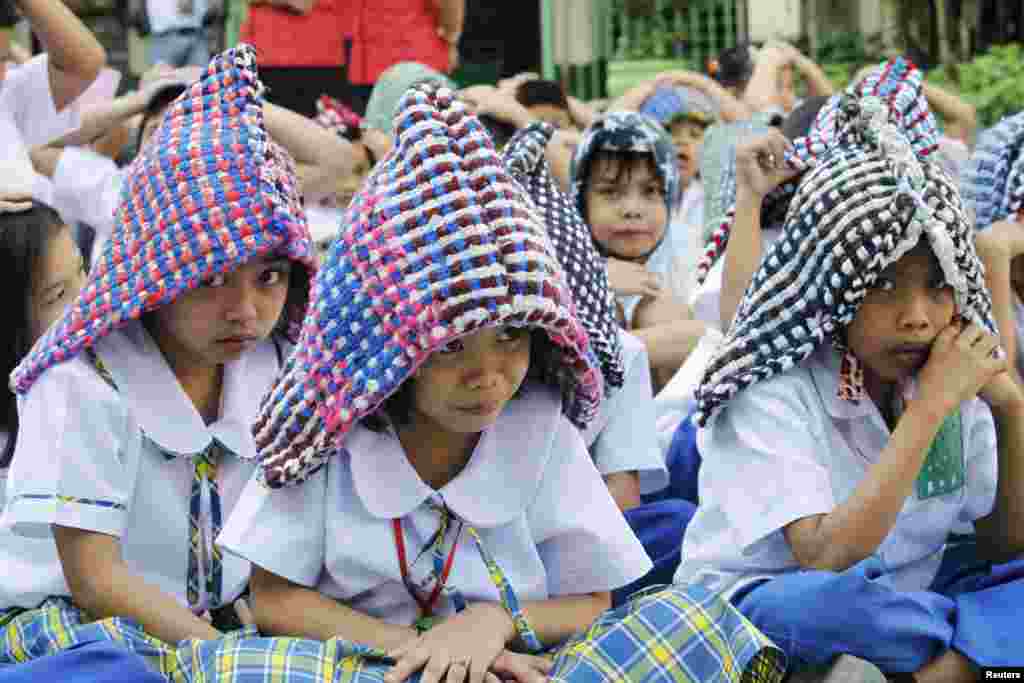 Siswa sekolah dasar menggunakan keset yang digunakan untuk melindungi kepala mereka dalam latihan menghadapi gempa bumi di kota Paranaque, Manila. Latihan tersebut bertujuan mengajarkan siswa dan staf sekolah bagaimana cara merespon gempa intensitas tinggi.