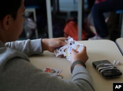 FILE - A student looks at his World Cup stickers in his Portuguese class, in Sao Paulo, Brazil, May 21, 2018.
