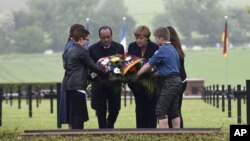 French President Francois Hollande, left, and German Chancellor Angela Merkel lay a wreath at a German cemetery in Consenvoye, northeastern France, May 29, 2016, during a remembrance ceremony to mark the centenary of the battle of Verdun. 