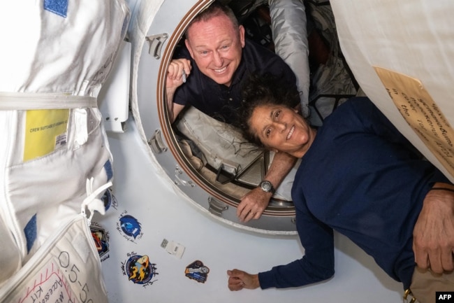 This undated handout picture from Nasa released on July 2, 2024 shows NASA’s Boeing Crew Flight Test astronauts (from top) Butch Wilmore and Suni Williams inside the vestibule between the International Space Station’s Harmony module and Boeing's Starliner spacecraft.