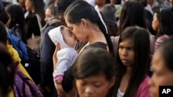 A Typhoon Haiyan survivor kisses her baby as she waits to board her evacuation flight at the airport in Tacloban, Philippines, Nov. 22, 2013. 