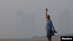 FILE—A man exercises amid smog, with buildings in the background, as air pollution levels rise in Karachi, Pakistan, November 10, 2023.