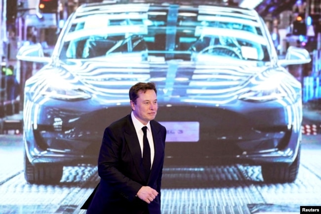CEO Tesla Inc Elon Musk berjalan di samping layar yang menunjukkan gambar mobil Tesla Model 3 buatan Tesla China di Shanghai. (Foto: Reuters)