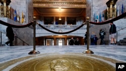 FILE - In this March 8, 2018, photo, visitors walk past the Washington state seal in the Capitol Rotunda in Olympia, Washington. Washington's legislative session is over but the conversation about sexual harassment at the state Capitol continues.