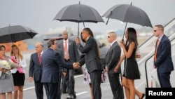 Presiden Obama (tengah) berjabat tangan dengan Menlu Kuba Bruno Rodriguez setibanya keluarga Presiden Amerika tiba di bandara Internasional di Havana, Kuba (20/3).