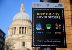 FILE - A public health information sign is seen with St. Paul's Cathedral seen behind amidst a lockdown during the spread of the coronavirus disease (COVID-19) pandemic, London, Britain, Jan. 7, 2021.