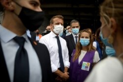 FILE - French President Emmanuel Macron, second from left, listen to members of local NGOs unloading emergency aid delivered for Lebanon at Beirut port, Sept. 1, 2020.