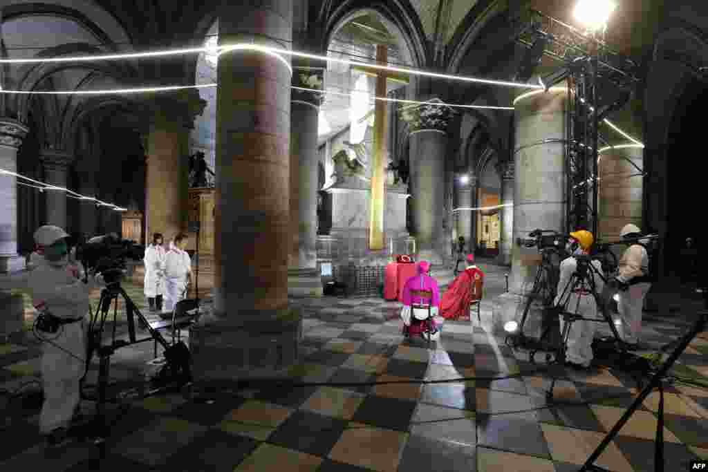 Journalists document a meditation ceremony to celebrate Good Friday in a secured part of Notre-Dame de Paris cathedral in Paris on the 25th day of a strict lockdown aimed at curbing the spread of the COVID-19 pandemic. 