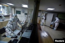 FILE - Medical workers in protective suits work inside an isolated section at a community health service center, in Qingshan district of Wuhan, Hubei province, China, Feb. 8, 2020.