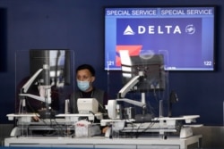 FILE - An agent works the counter at the Delta Air Lines terminal at the Los Angeles International Airport, May 28, 2020.