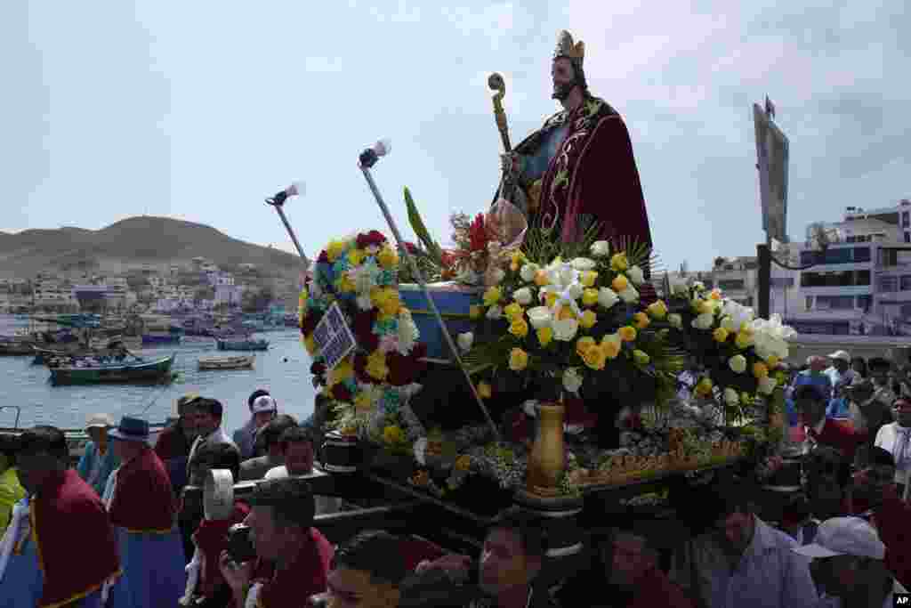 Pescadores van en procesión detrás de la representación de San Pedro, transportada en un bote, en el centro, como parte de la procesión por el océano Pacífico en honor del santo patrón católico de los pescadores en el día de su festividad en Pucusana, Perú, el jueves 29 de junio de 2023.