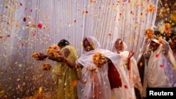 Widows throw flowers into the air during a holi celebration at the Meera Sahavagini ashram in Vrindavan in the northern Indian state of Uttar Pradesh, Mar. 24, 2013.