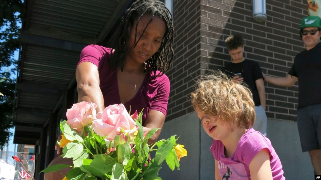 Angel Sauls (left) helps her stepdaughter, Coco Douglas, arrange a sign and some painted rocks she made for a memorial in Portland, Ore., May 27, 2017.