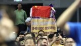 A fan drapes a Chinese national flag over an NBA banner during a preseason NBA basketball game between the Brooklyn Nets and Los Angeles Lakers at the Mercedes Benz Arena in Shanghai, China, Oct. 10, 2019.