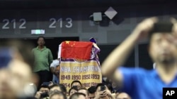 A fan drapes a Chinese national flag over an NBA banner during a preseason NBA basketball game between the Brooklyn Nets and Los Angeles Lakers at the Mercedes Benz Arena in Shanghai, China, Oct. 10, 2019.