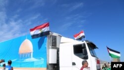 TOPSHOT - People on the Egyptian side of the Rafah border crossing cheer as a convoy of lorries carrying humanitarian aid crosses to the Gaza Strip on October 21, 2023.