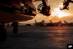 FILE - In this Russian Defense Ministry Press Service photo, a Russian Su-25 ground attack jet is parked at Hemeimeem air base in Syria, with Su-24 bombers seen in the background, Dec. 18, 2015.