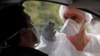 A medical worker administers a nasal swab to a patient at a drive-through testing site for coronavirus disease (COVID-19) near the hospital in Laval, France, July 15, 2020.