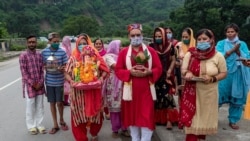 Devotees wearing masks as precaution against the coronavirus walk carrying an idol of Hindu god Ganesha to immerse in a water body, after worshipping the same at a village near Kangra, south of Dharmsala, India, Sunday, Aug. 30, 2020. (AP Photo…