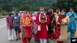 30일 인도 다람살라 남쪽 캉그라 마을에서 주민들이 마스크를 쓴 채 인도 신 가네샤 동상을 들고 행진하고 있다. 